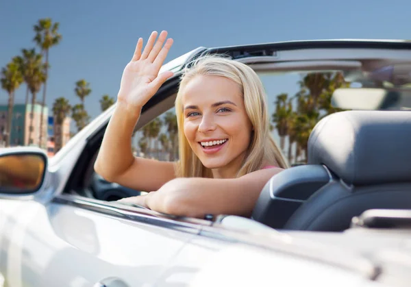 Happy young woman in convertible car waving hand — Stock Photo, Image