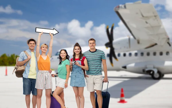 Friends with travel bags and arrow over airplane — Stock Photo, Image