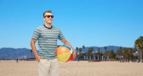 Joven sonriente en gafas de sol con pelota de playa — Foto de Stock