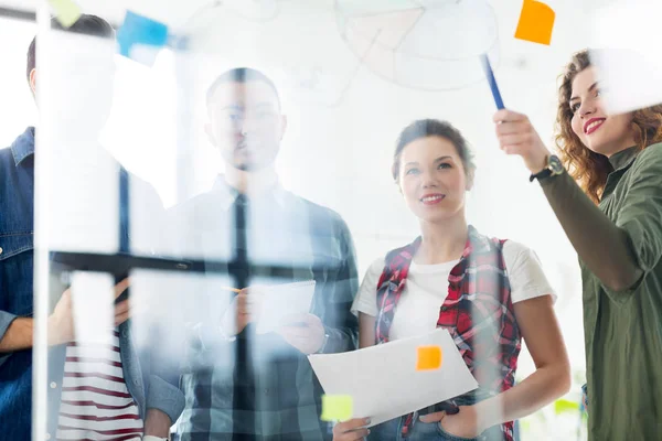 Equipo creativo escribiendo en tablero de cristal en la oficina — Foto de Stock