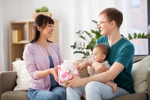 Evde hediye ve bebek çocukla mutlu aile — Stok fotoğraf