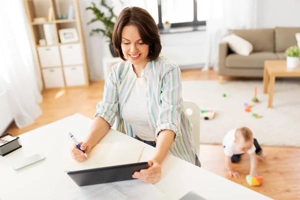 Werkende moeder met tablet pc en baby thuis — Stockfoto