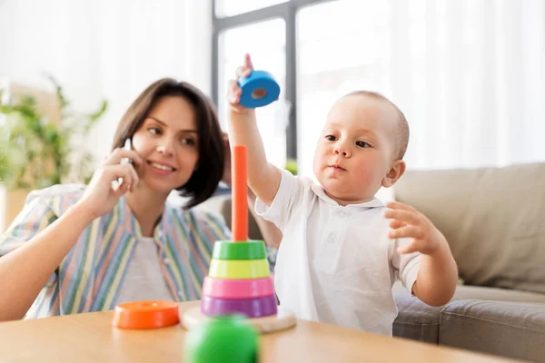 Bebé niño jugando juguete y madre llamando por teléfono — Foto de Stock