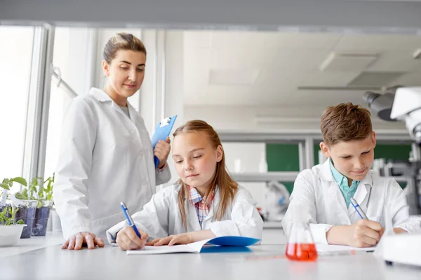 Lärare och studenter som studerar kemi i skolan — Stockfoto