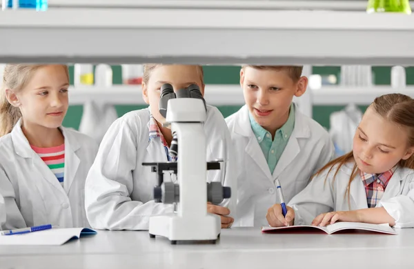 Niños o estudiantes con biología de microscopio en la escuela — Foto de Stock
