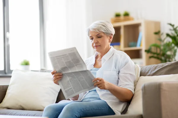 Mulher sênior ler jornal em casa — Fotografia de Stock