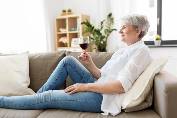 Senior woman with glass of red wine at home — Stock Photo, Image