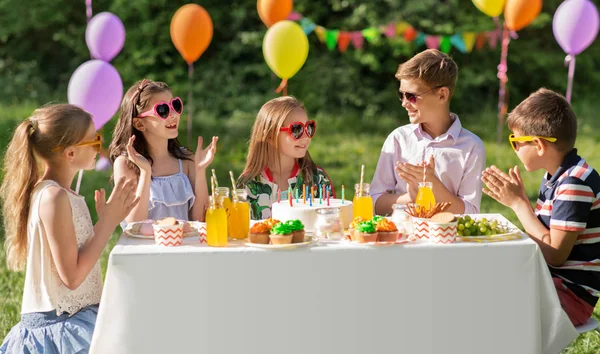 Niños felices con pastel en la fiesta de cumpleaños en verano —  Fotos de Stock