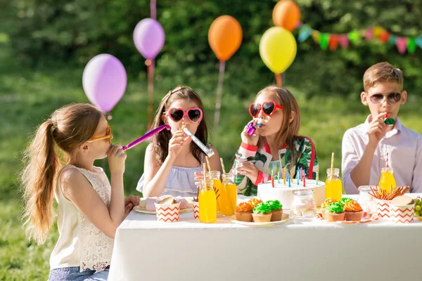 Enfants heureux soufflant cornes de fête à l'anniversaire d'été — Photo