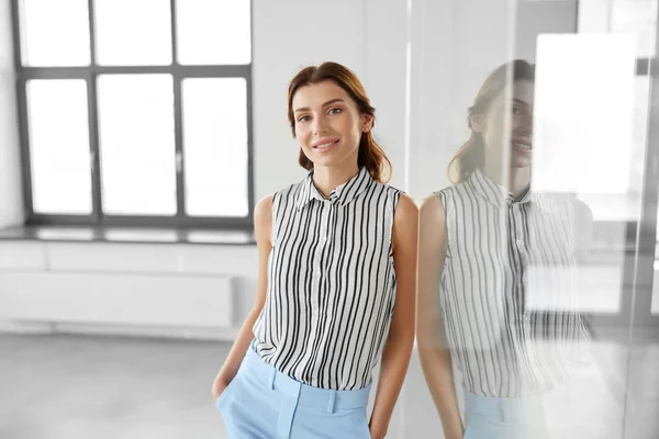 Mujer de negocios sonriente en la pared de cristal de oficina — Foto de Stock