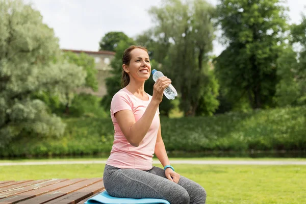 Mujer bebiendo agua después de hacer ejercicio en el parque — Foto de Stock