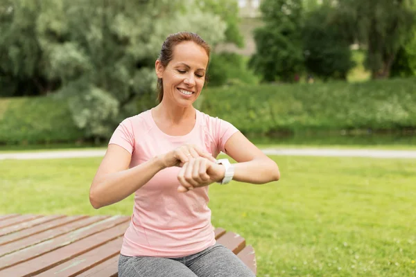 Mujer con reloj inteligente o rastreador de fitness en el parque —  Fotos de Stock