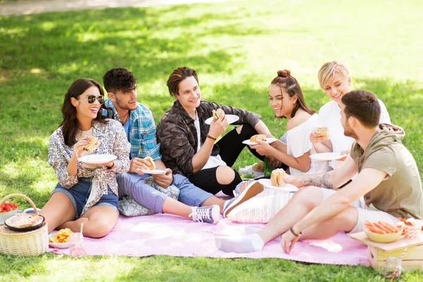 Amici felici mangiare panini al picnic estivo — Foto Stock