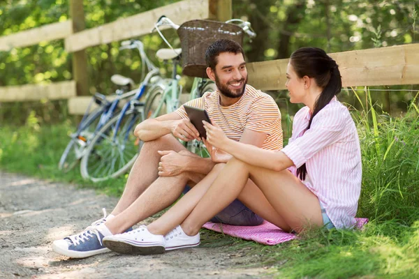 Пара с планшетным ПК и велосипеды в летнем парке — стоковое фото