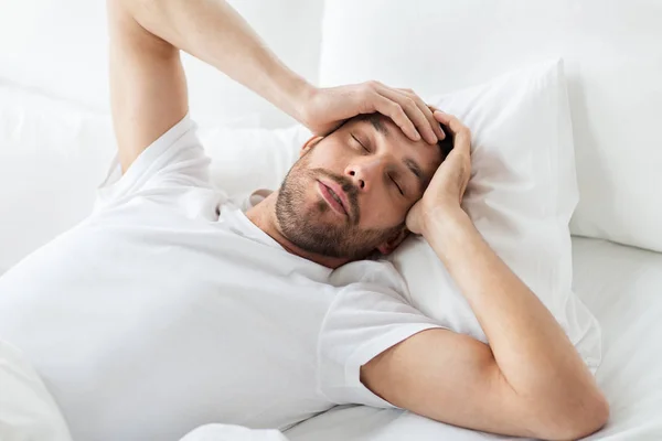 Hombre en la cama en casa sufriendo de dolor de cabeza — Foto de Stock