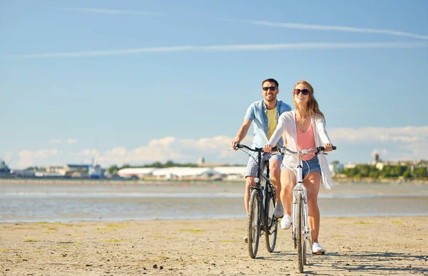 海辺で自転車に乗って幸せな若いカップル — ストック写真