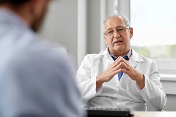 Médico sênior falando com paciente do sexo masculino no hospital — Fotografia de Stock