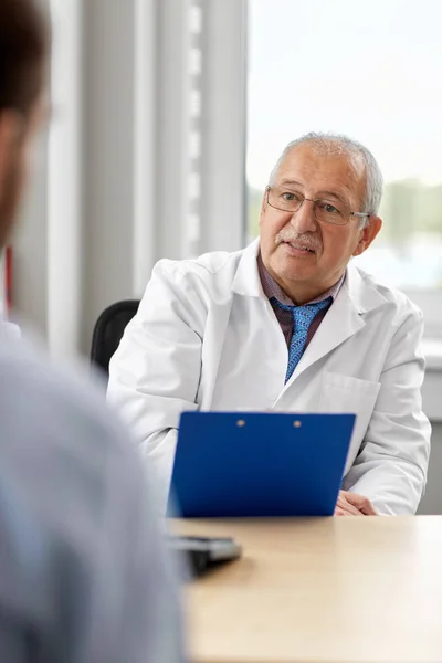 Médico sênior falando com paciente do sexo masculino no hospital — Fotografia de Stock