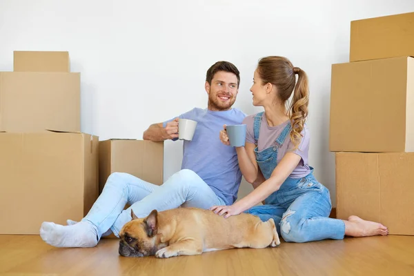 Feliz pareja con cajas y perro mudándose a un nuevo hogar —  Fotos de Stock