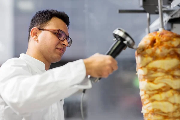 Chef rebanando carne doner de escupir en la tienda de kebab —  Fotos de Stock