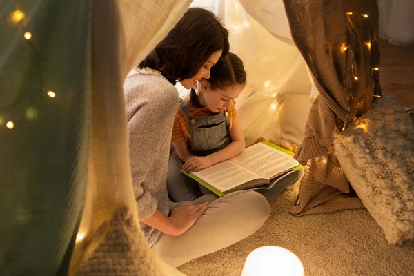 Happy family reading book in kids tent at home — Stock Photo, Image