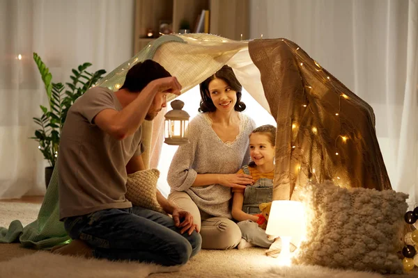 Famiglia felice che gioca nella tenda dei bambini di notte a casa — Foto Stock