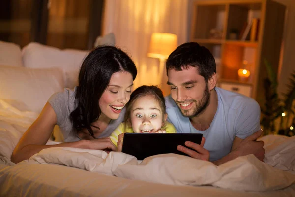 Família com tablet pc na cama à noite em casa — Fotografia de Stock