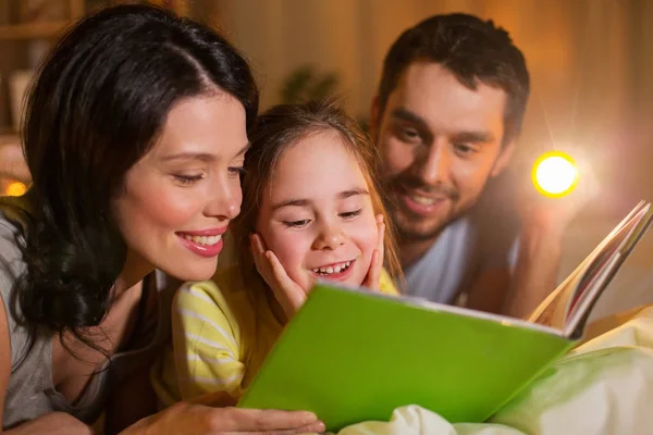 Gelukkige familie leesboek in bed bij nacht thuis — Stockfoto