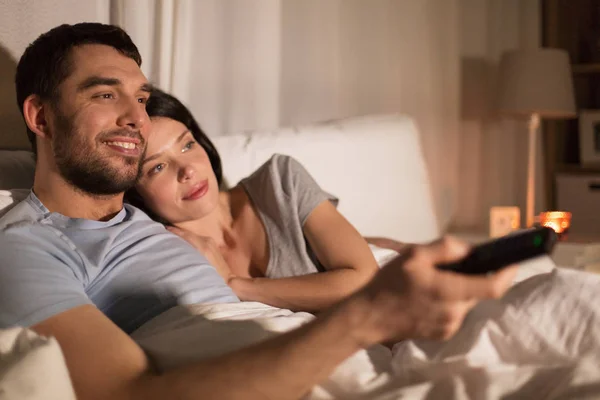 Happy couple watching tv in bed at night at home — Stock Photo, Image