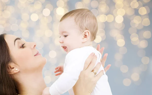 Mãe com bebê sobre luzes festivas fundo — Fotografia de Stock