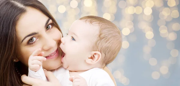 Madre con el bebé sobre el fondo de luces festivas — Foto de Stock