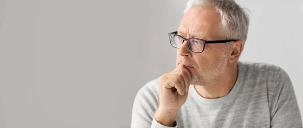 Close up of senior man in glasses thinking — Stock Photo, Image