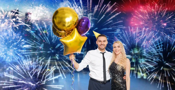 Paar mit Partymützen und Luftballons über Feuerwerk — Stockfoto