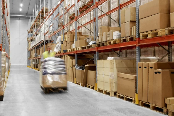 Trabalhador carregando carregador com mercadorias no armazém — Fotografia de Stock