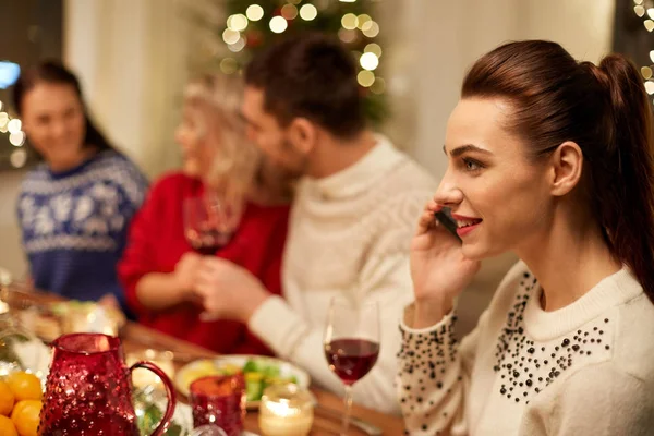 Kobieta dzwoni na smartfona podczas świątecznej kolacji — Zdjęcie stockowe