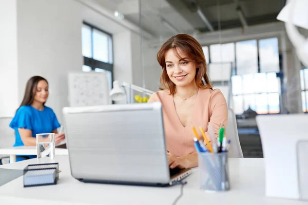 Счастливая деловая женщина с ноутбуком работает в офисе — стоковое фото