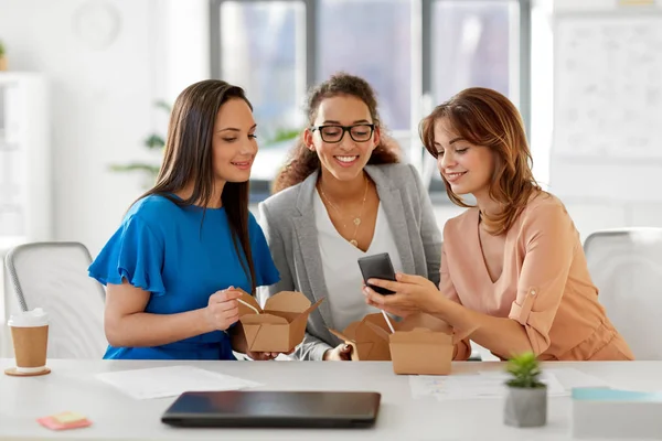 Businesswomen with smartphone at lunch in office — Stock Photo, Image