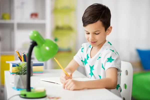 Szczęśliwy, mały chłopiec, w piśmie do notebooka w domu — Zdjęcie stockowe