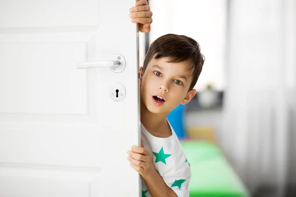 Überrascht kleinen Jungen hinter Tür zu Hause — Stockfoto