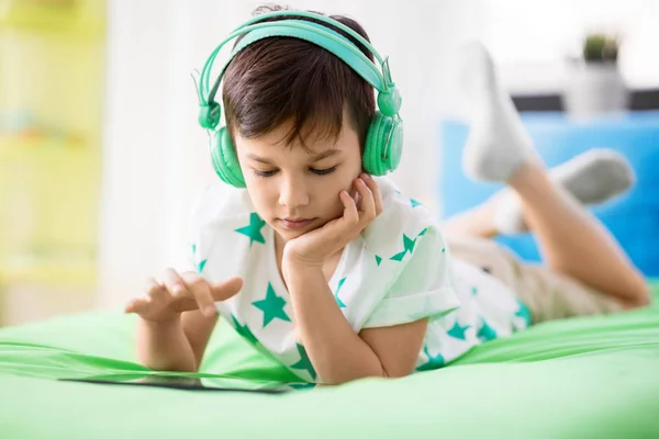 Niño con tablet PC y auriculares en casa —  Fotos de Stock