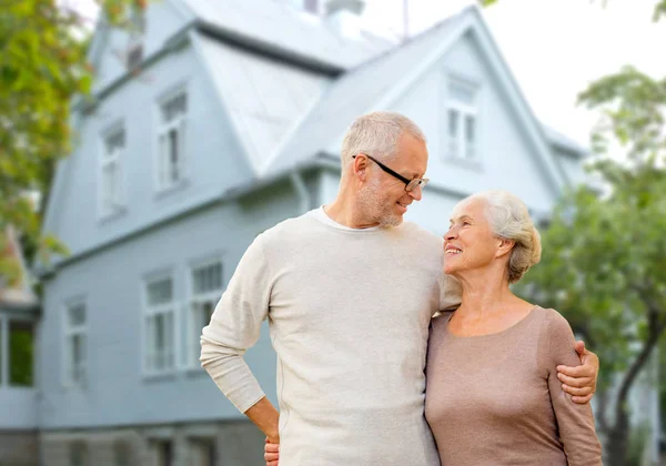 Glückliches Senioren-Paar umarmt sich vor Haus-Hintergrund — Stockfoto