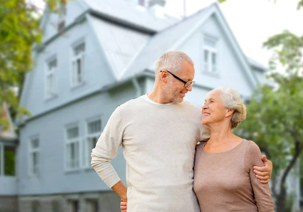 Feliz casal sênior abraçando sobre o fundo da casa — Fotografia de Stock