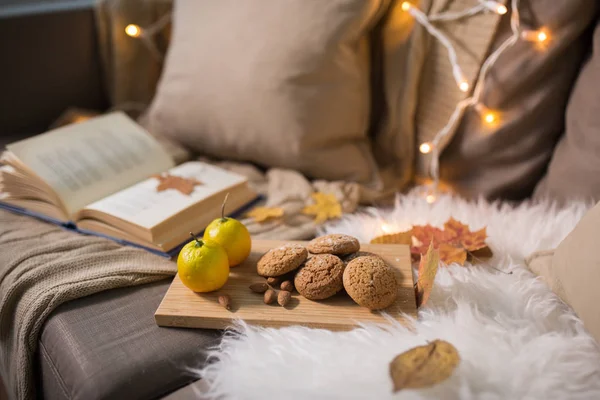 Zitronen, Buch, Mandel- und Haferkekse auf dem Sofa — Stockfoto