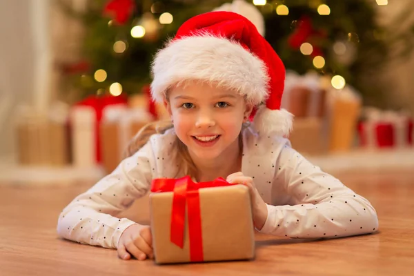 Leende flicka i tomte hatt med julklapp — Stockfoto