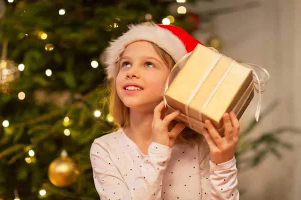 Sorrindo menina em santa chapéu com presente de Natal — Fotografia de Stock