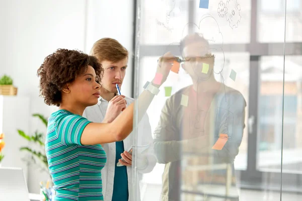 Kreatives Team schreibt auf Glastafel im Büro — Stockfoto