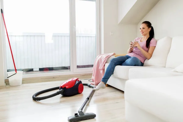 Mujer con aspiradora bebiendo café en casa —  Fotos de Stock