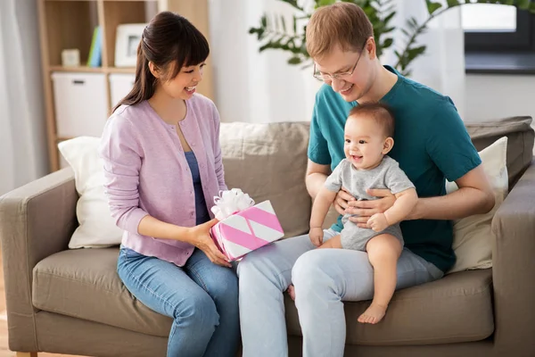 Glückliche Familie mit Geschenk und Baby zu Hause — Stockfoto