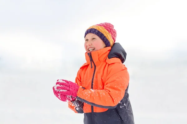 Fille heureuse jouant avec la neige en hiver Image En Vente