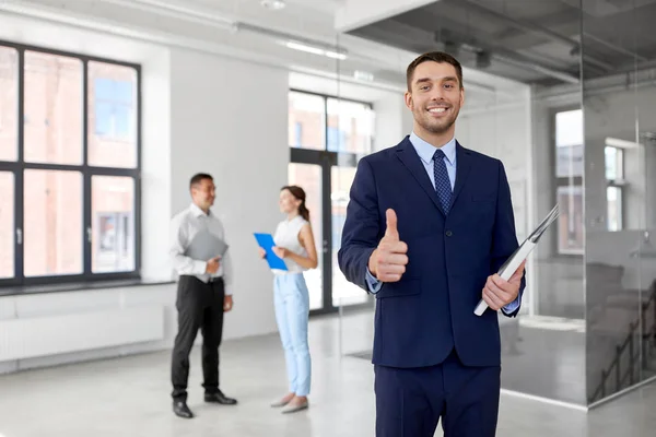 Realtor with folder showing thumbs up at office — Stock Photo, Image